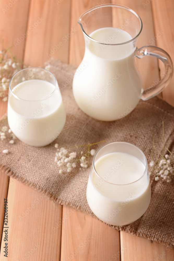 Composition with glasses and jug of tasty milk on wooden table Composition with glasses and jug of tasty milk on wooden table