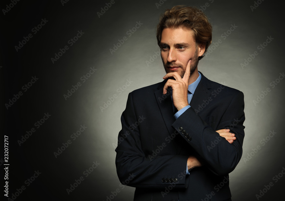 Thoughtful young businessman on dark background Thoughtful young businessman on dark background