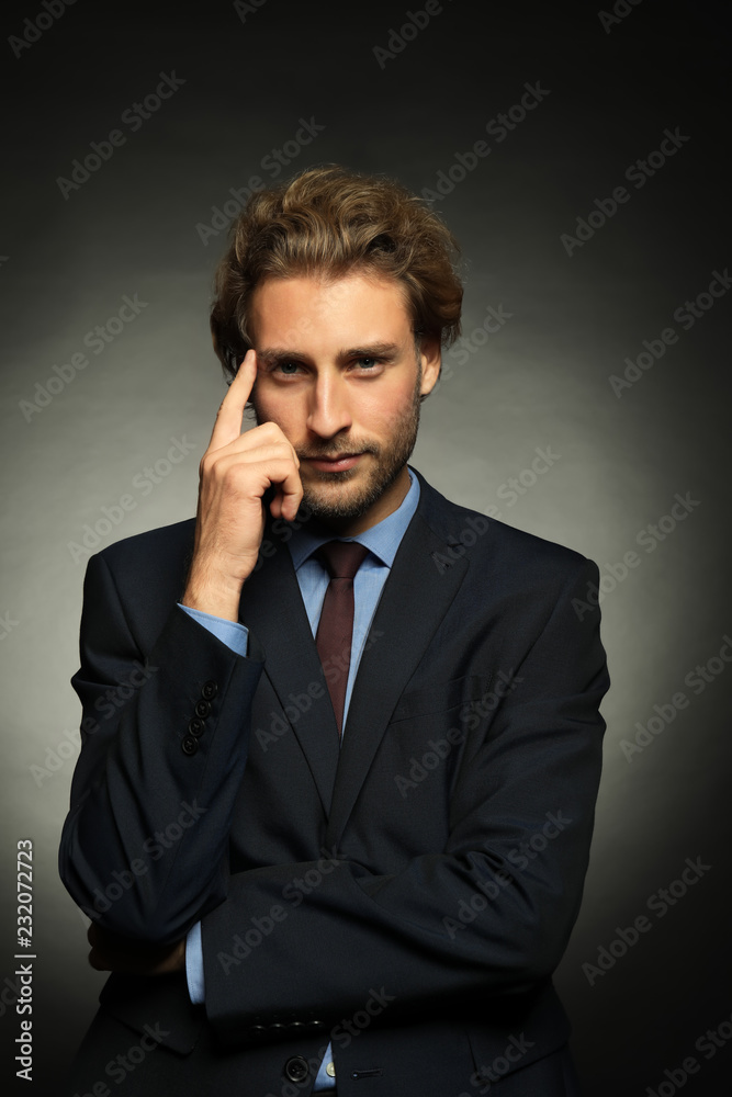 Thoughtful young businessman on dark background Thoughtful young businessman on dark background