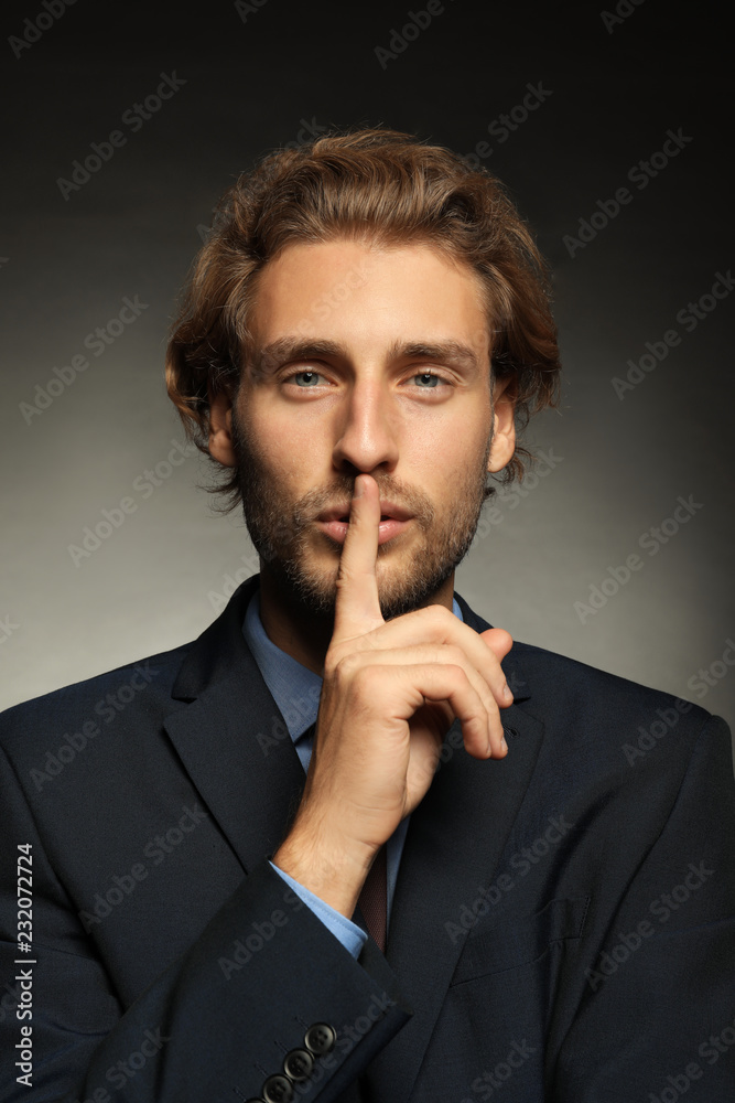 Portrait of young businessman showing silence gesture on black background Portrait of young businessman showing silence gesture on black background