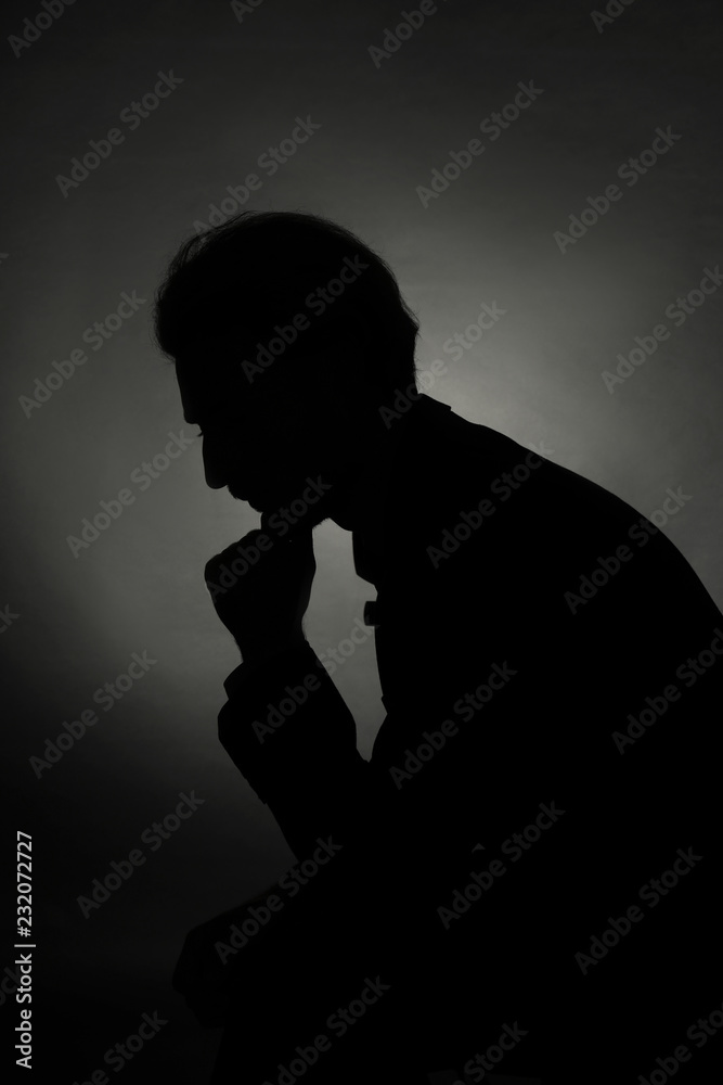Silhouette of young businessman in darkness