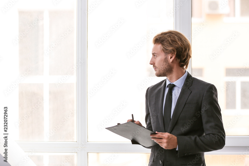 Confident businessman with clipboard near window Confident businessman with clipboard near window