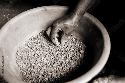 skinny african person hand touching pot of beans in african during difficult famine time in village with sepia effect photo