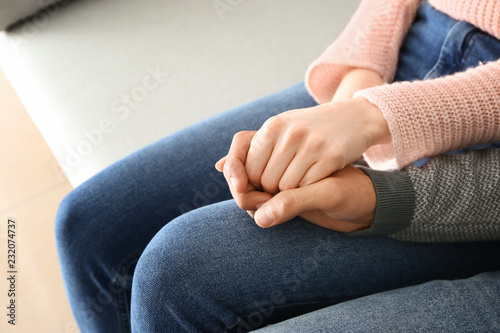 Loving young couple holding hands while sitting on sofa, closeup