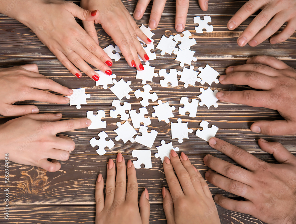 Group of people doing puzzle on table Group of people doing puzzle on table