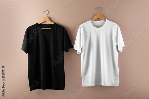 Hangers with blank t-shirts on color background