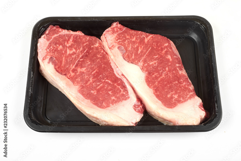 Raw sirloin beef steak in plastic packaging tray.