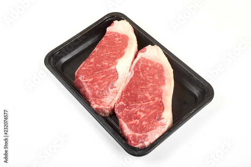 Raw sirloin beef steak in plastic packaging tray.