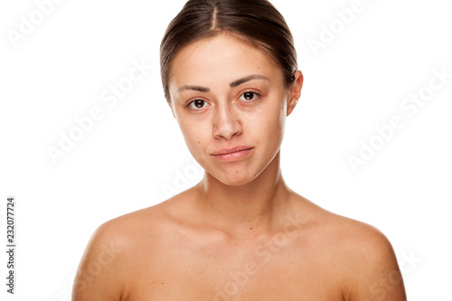 Portrait of young beautiful sad woman with no makeup on white background