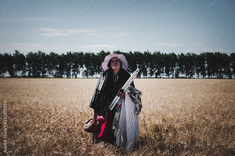girl in a hat and glasses against the background of a wheat field and trees