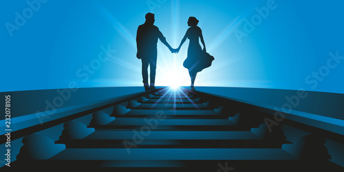 Un couple d'amoureux se promène, main dans la main, le long d'une voix ferrée en direction de l'horizon face au soleil.