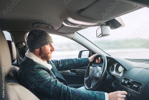 Warm dressed Bearded Man driving a new modern auto. Inside car view. © Soloviova Liudmyla