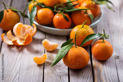Tangerines, mandarin fresh citrus fruits with leaves on wooden background