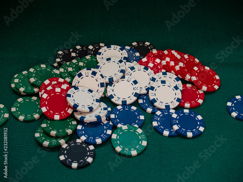 Poker chips of various colors on a green mat