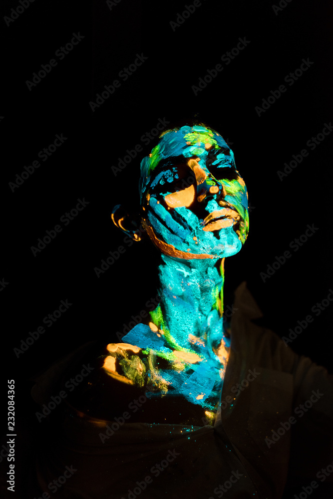 model with colorful neon paints on body posing on black backdrop