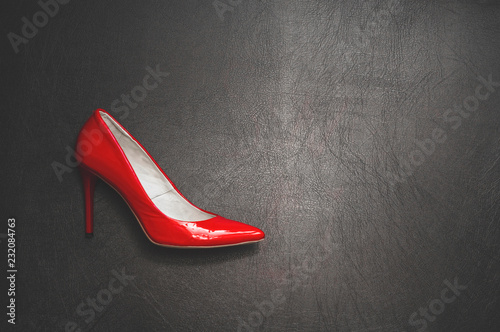 Black and red. Lacquered red shoe on a hairpin on a black background