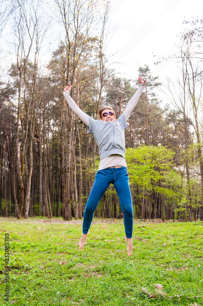 Girl with sunglasses jumping on the grass lawn Girl with sunglasses jumping on the grass lawn