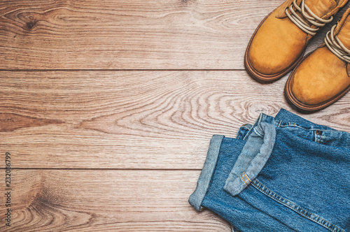  Jeans and yellow boots on a wooden background. Top view