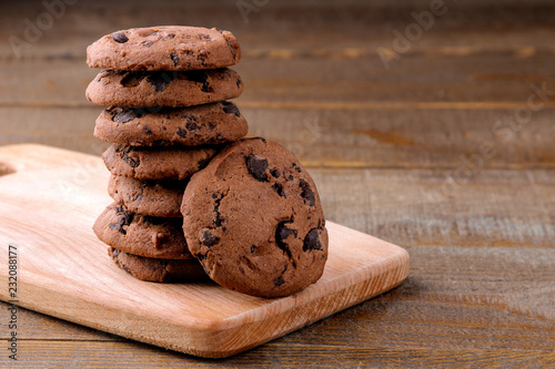 Tasty cookies with chocolate on the board on a brown wooden table