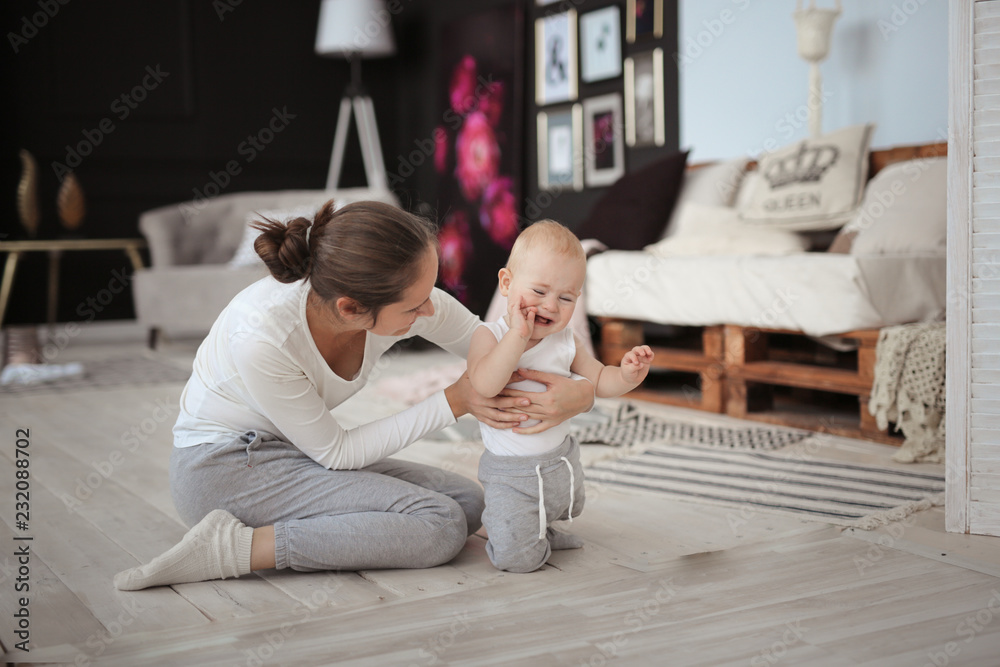 Obraz premium Mother comforts crying baby on floor in room.