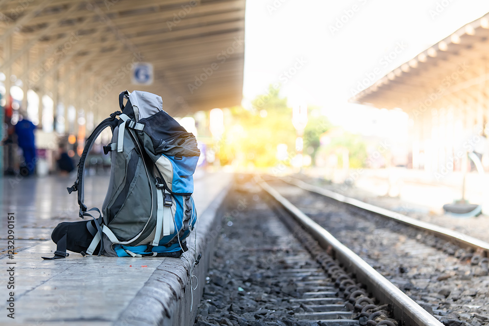 Travel and transportation concept :Tourists backpack on  on railway station with sun light blured background.