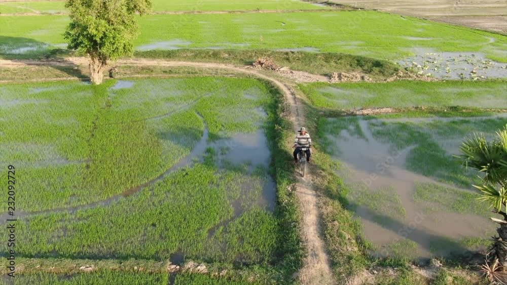 Low aerial drone view of worker riding a motorcycle along the berm of a ...