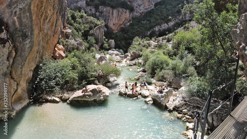 People having bath in a small pond of the Vero river among rocks and cliffs of the Vero canyon and mountains in Alquezar, Spain