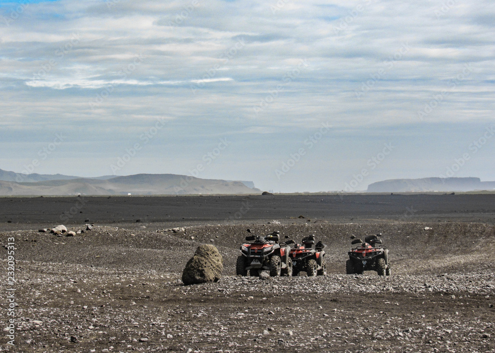 Four quad bikes in Solheimasandur plane wreck place: black sand desert landscape in South Iceland, Europe