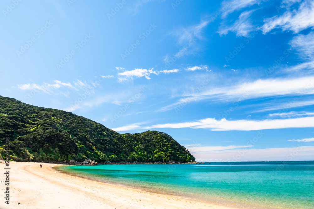 People walking on the beautiful beach along the coastline in Abel Tasman National Park, South Island, New Zealand.