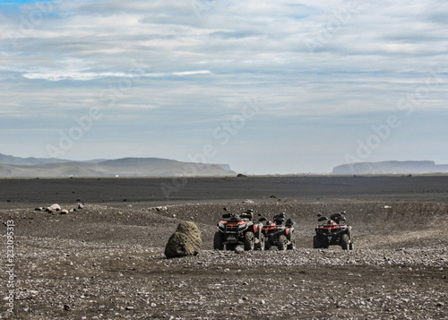 Four quad bikes in Solheimasandur plane wreck place: black sand desert landscape in South Iceland, Europe photo