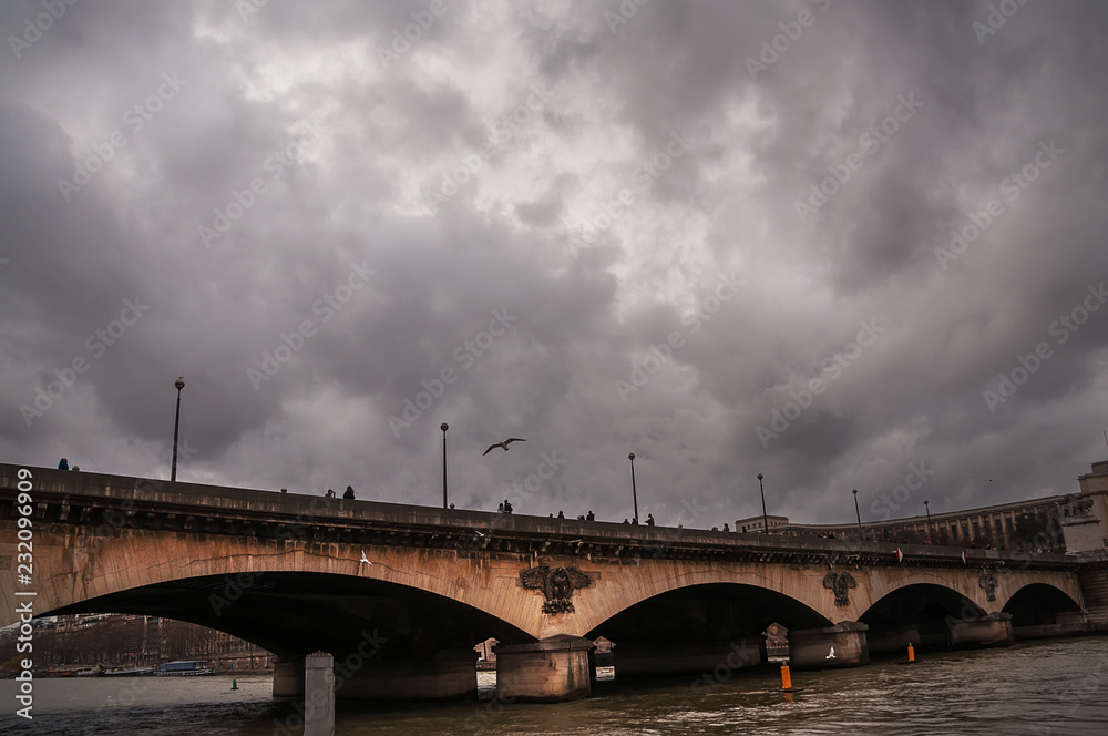 Fototapeta premium Bridge over the river in Paris and dramatic sky. 