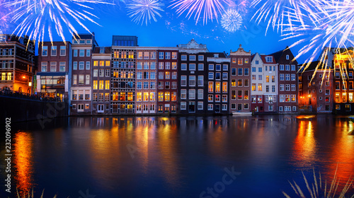 Photography Houses facades over canal with reflections illuminated at night with fireworks,
