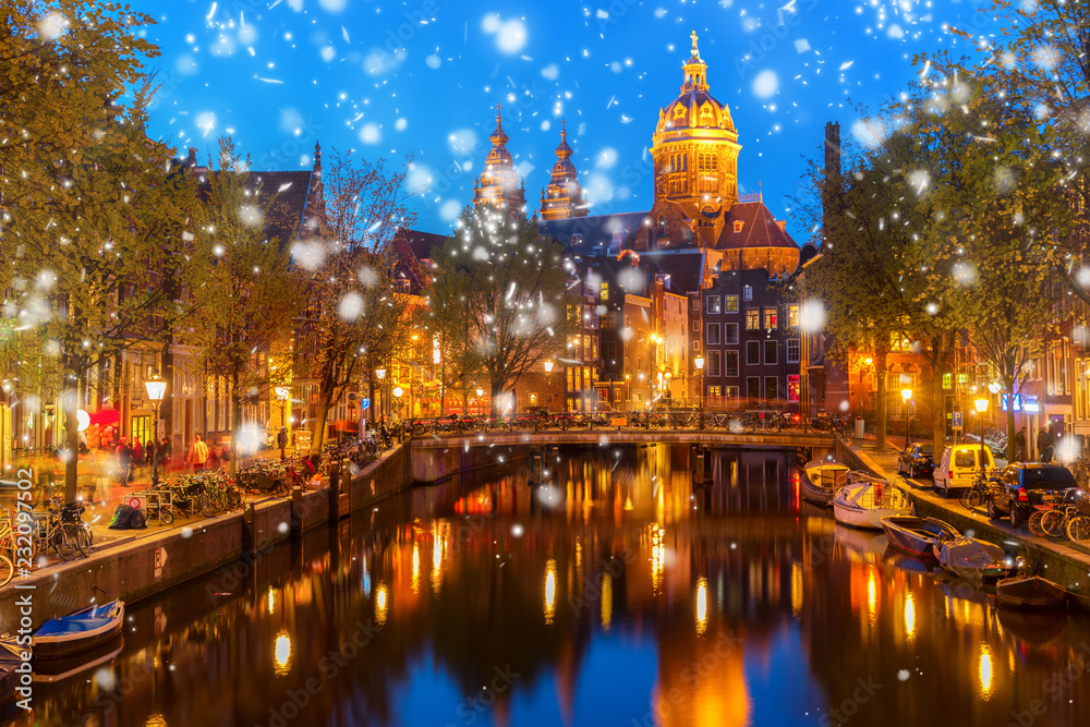 Church of St Nicholas over old town canal illuminated at night with snow, Amsterdam, Holland