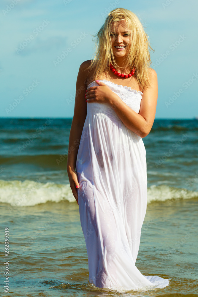 Blonde woman wearing dress walking in water Blonde woman wearing dress walking in water