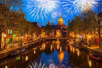 Church of St Nicholas and red lights quater over old town canal at night with fireworks, Amsterdam, Holland