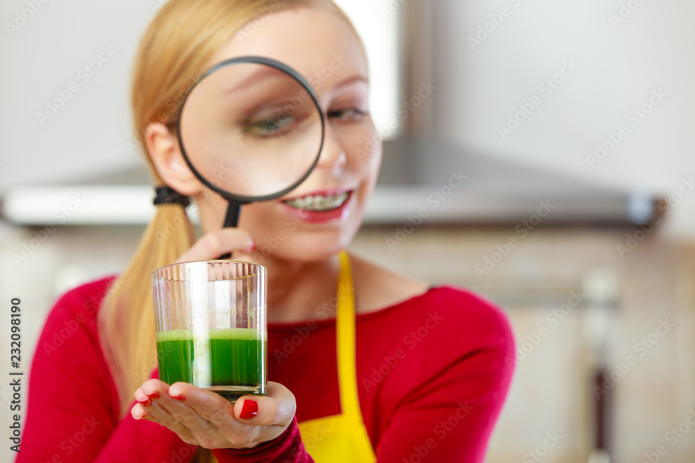 Woman looking at vegetable juice through magnifying glass Woman looking at vegetable juice through magnifying glass