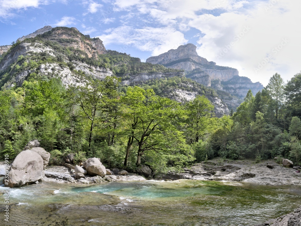 Fototapeta premium The waterfalls and the rapids in the Rio Bellos canyon on the forest covered rocky mountains in the Cañon de Añisclo valley, in Aragon region, Spain