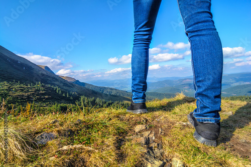 Traveler-girl travels in the mountains. Close-up of feet on the ground