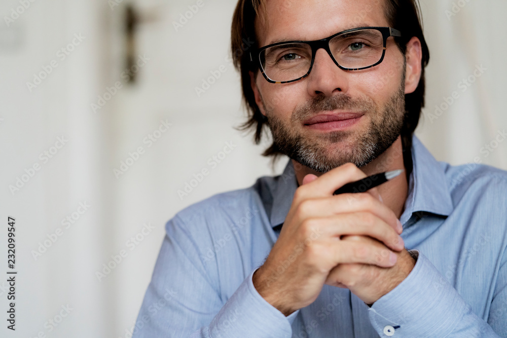 Portrait of confident man wearing glasses and holding pen Portrait of confident man wearing glasses and holding pen
