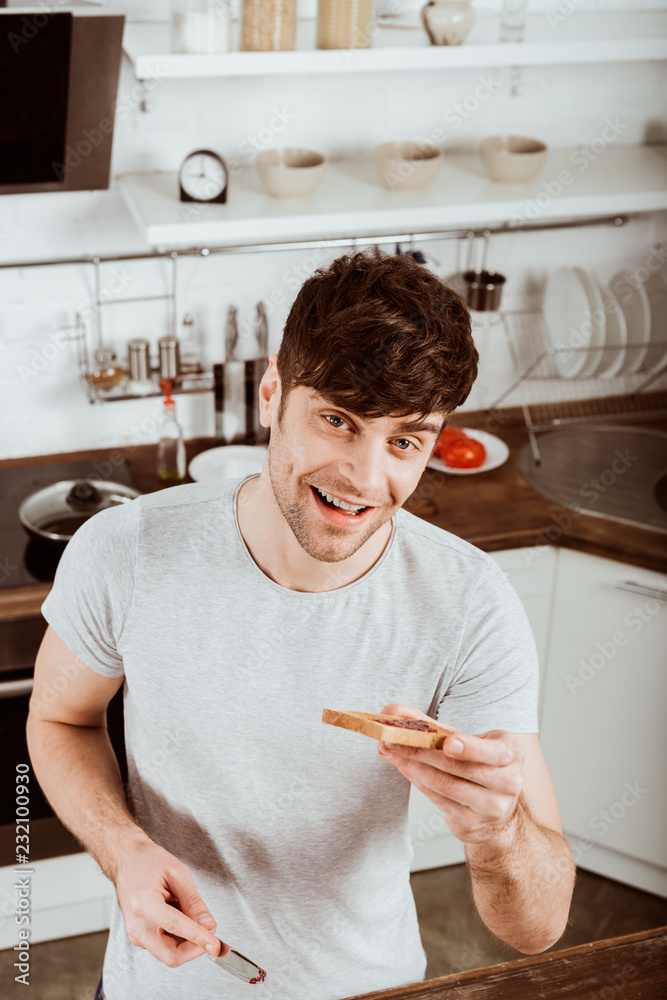 high angle view of young man having eating toast with jam on breakfast at kitchen