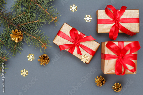 Gift boxes, fir tree branches with cones on gray background