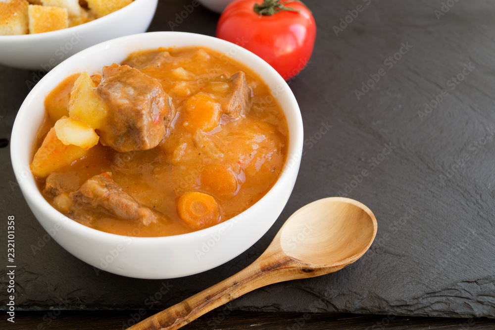 thick Hungarian soup, the goulash. on dark background. thick Hungarian soup, the goulash. on dark background.