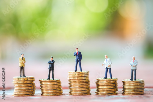 Many miniature business man on stack of coins. Concept of business and finance. photo