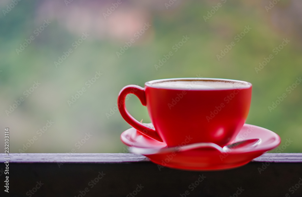 Red cup of coffee on black steel balcony rail with blur background
