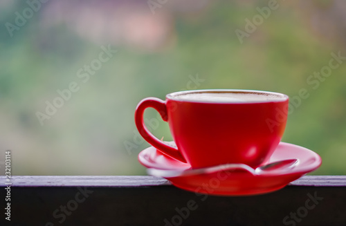 Red cup of coffee on black steel balcony rail with blur background