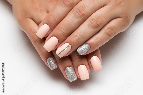 Peach manicure with silver glitters and stones  strip of crystals on long square nails close-up on a white background  