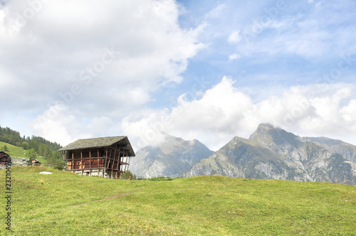 A wooden lodge in the Walser town of Dorf, among high mountains, pine forests and pastures, in summer, in Val d'Otro valley, Alps mountains, Italy photo