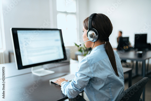 Photography Female customer service representative with headset working on computer