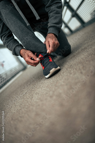 Runner tying his shoelaces after run.
