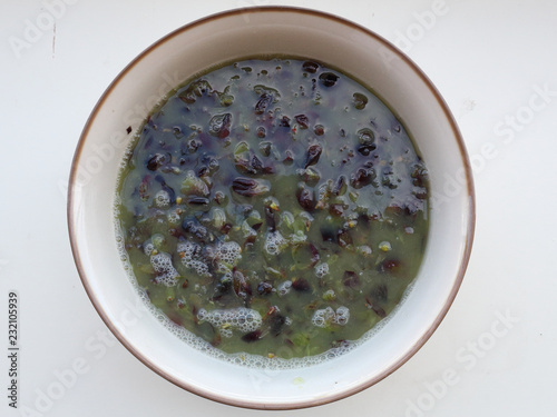 Recently stomped red grapes must in a white ceramic bowl on a white surface, an important step in the winemaking process photo